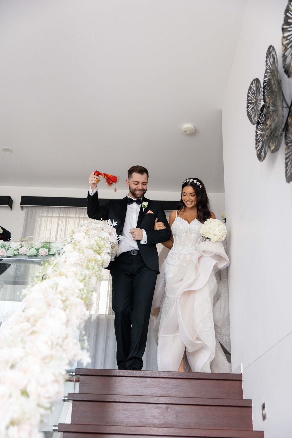 Bride and groom descending decorated staircase with red envelope at wedding reception.