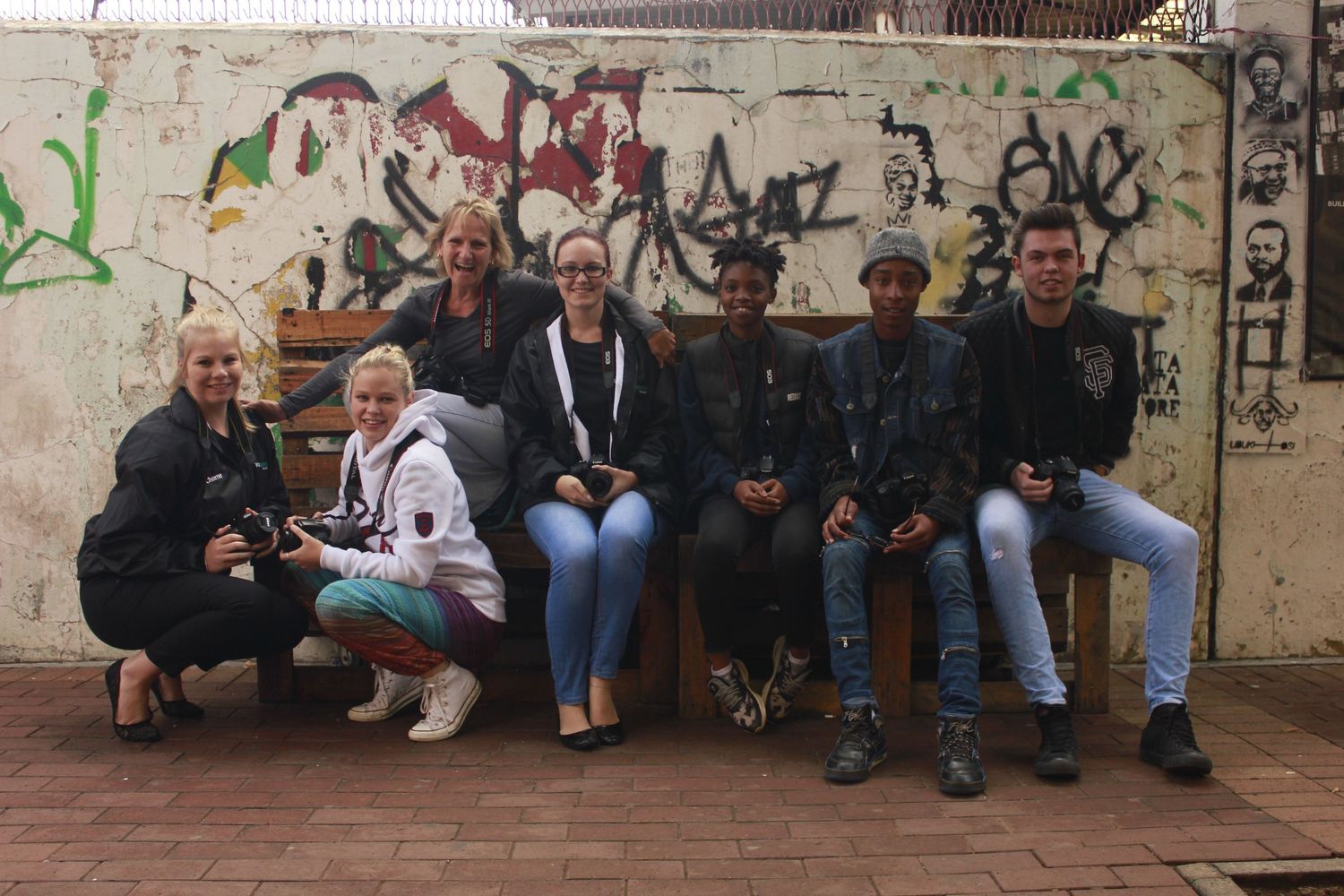 GETPIX 9-month photography students taking a break in front of a vibrant graffiti wall during an urban photography session.