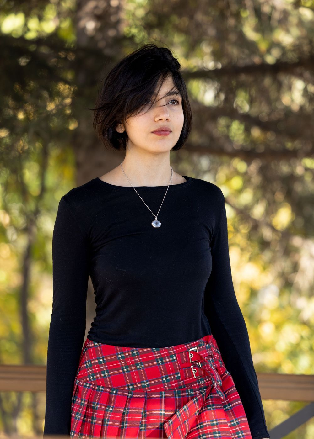 A series of fashion photos showing a black long sleeve top paired with a red plaid skirt in an outdoor setting.