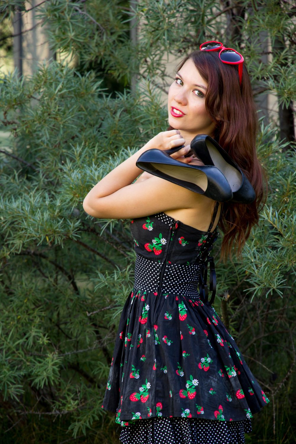 Retro-style polka dot and cherry print dress with black bodice and full skirt photographed in a garden setting.