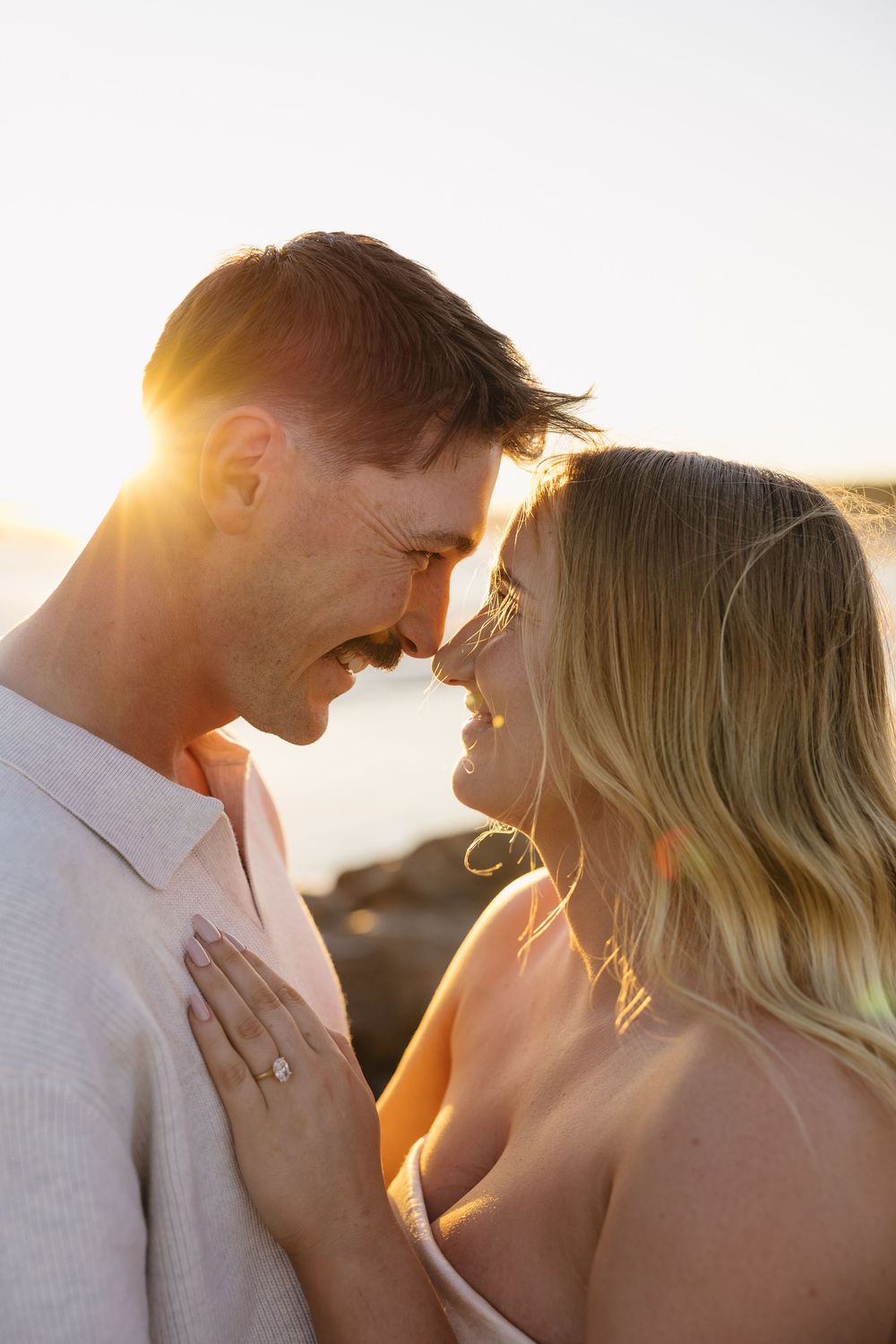 Romantic couple sharing an intimate moment at sunset with golden sunlight streaming between them.