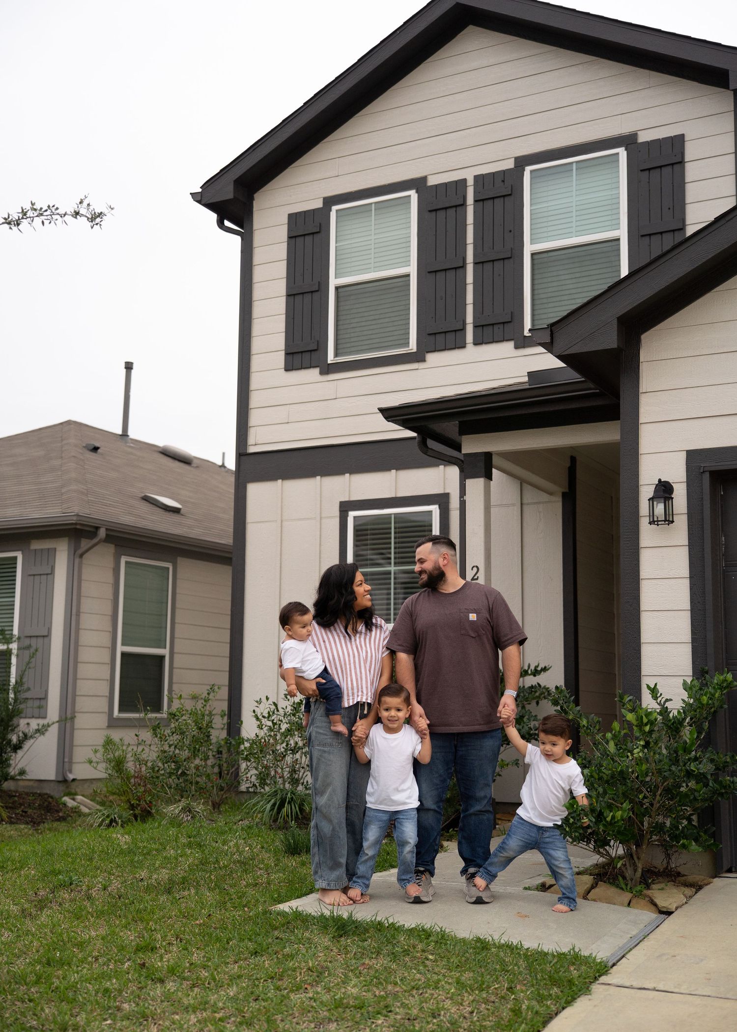Family portrait in empty home with natural light, showing love and connection as they prepare for a new baby
