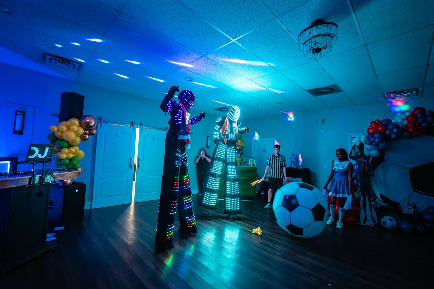 A blue-lit dance floor and DJ booth setup in an empty nightclub with party decorations and lighting effects.