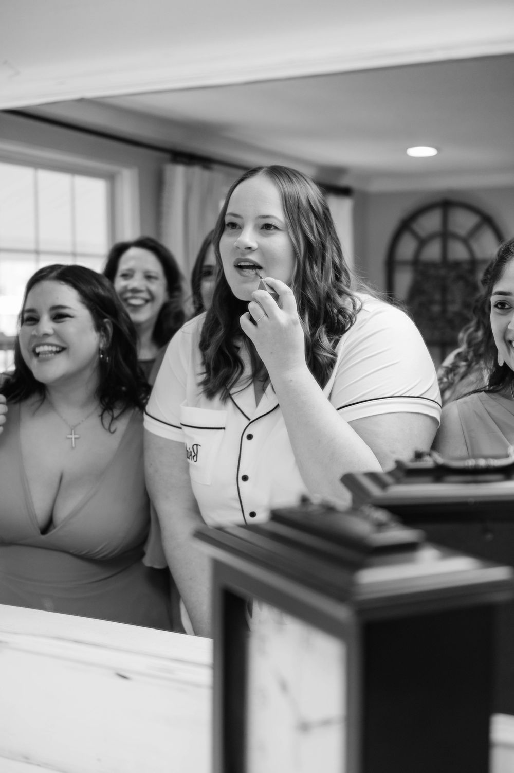 Black and white candid shots capture joyful laughter during wedding preparations.