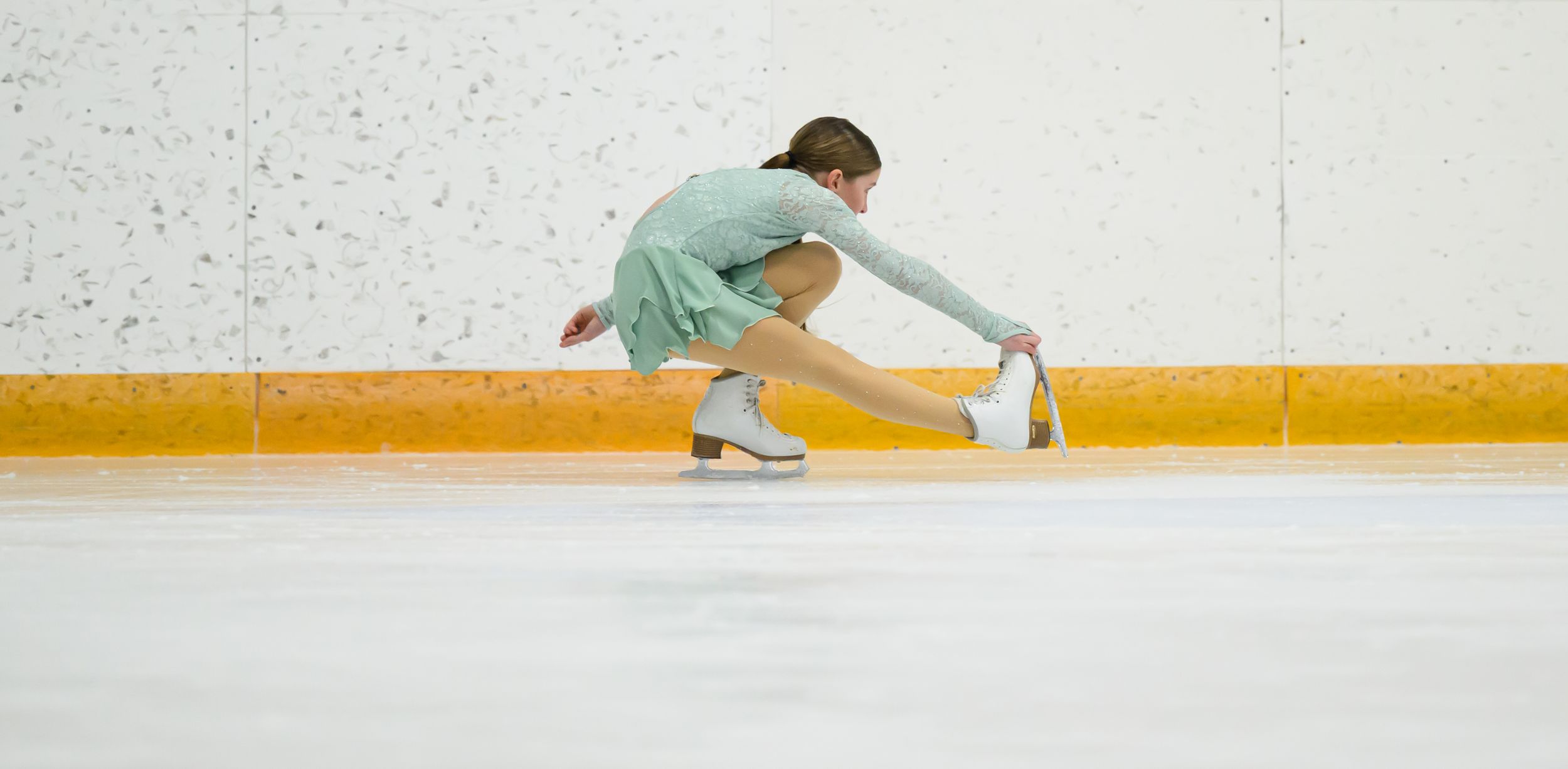 A figure skater performs a graceful spin on the ice rink with arms extended in an artistic pose.