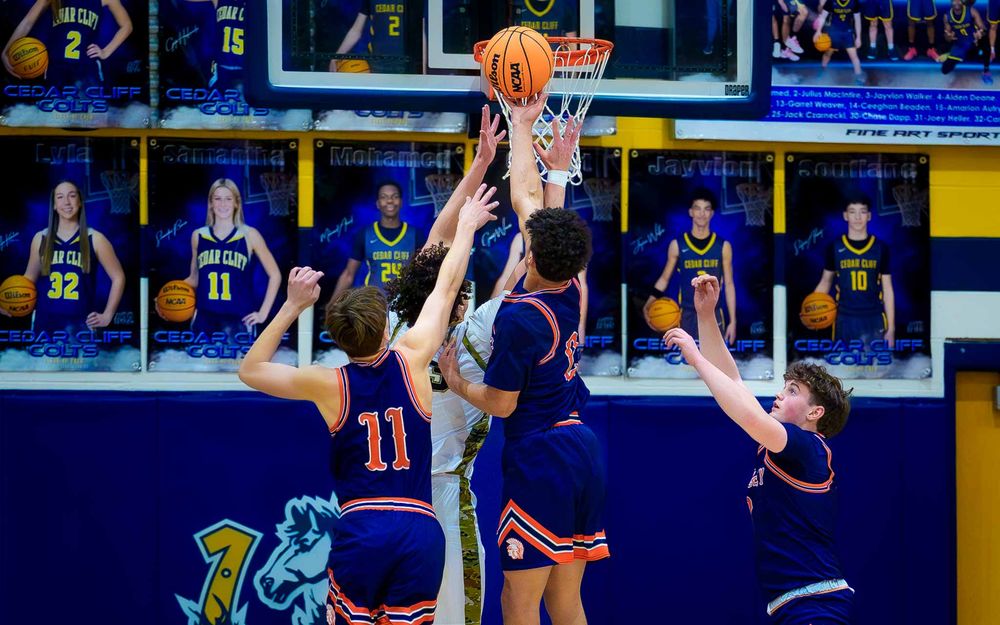 Hershey Trojans player jumps for a contested shot in the paint against multiple defenders by SportsFox Photography, Hershey PA.
