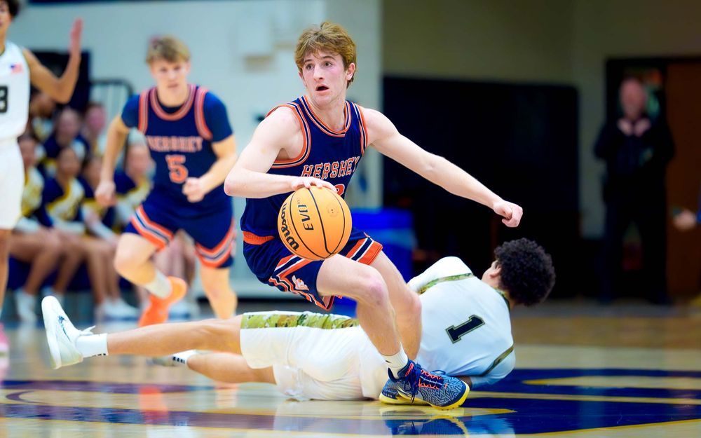 Hershey Trojans player dribbles past a defender on the court, aiming for the basket by SportsFox Photography, Hershey PA.