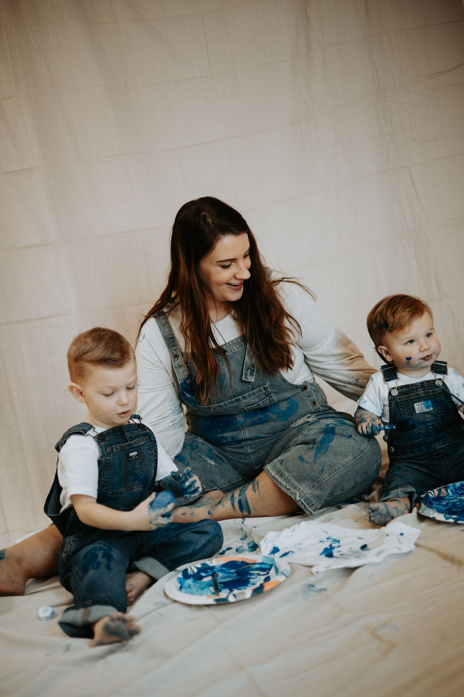 A playful sequence shows a parent and child in matching denim overalls creating art together on a white backdrop.