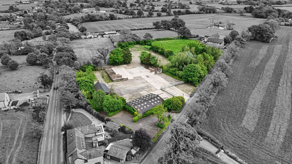 Black and white aerial panorama of rural farmland and scattered buildings.