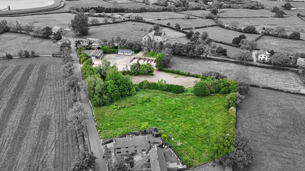 Aerial view of a property with green fields highlighted in color against black and white surroundings.