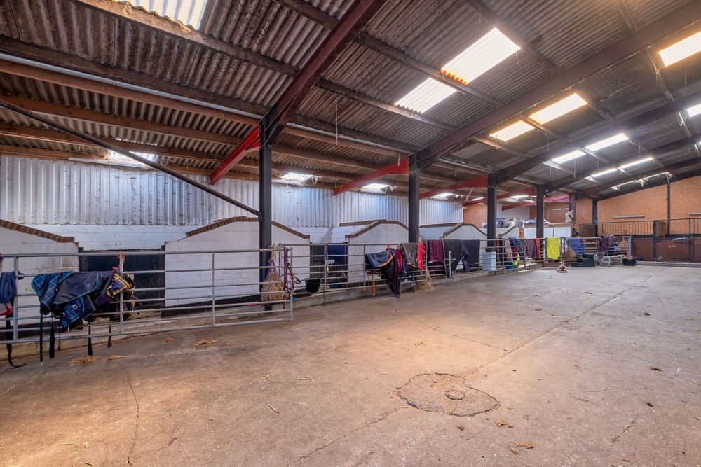 Large industrial barn interior with metal roof and equipment storage space.