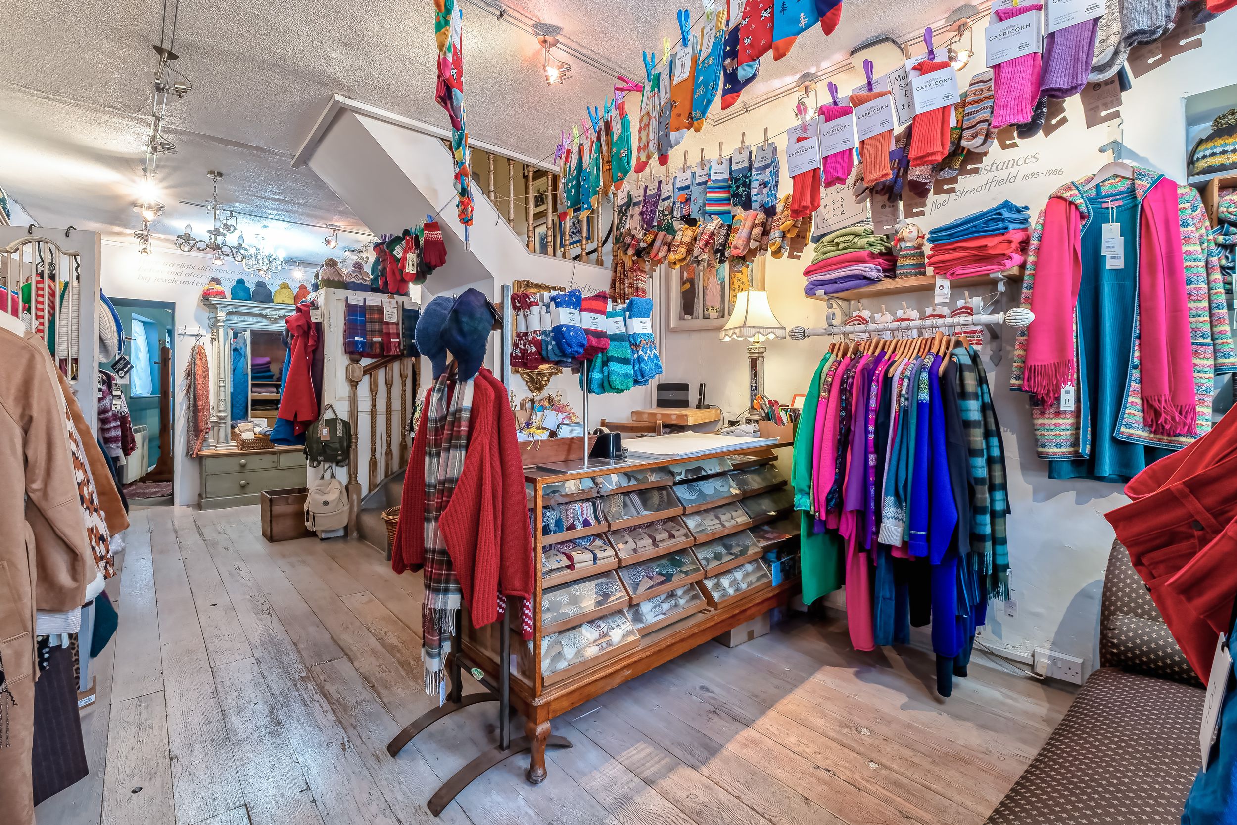 Interior view of a retail clothing store with colorful garments hanging on racks and displays.