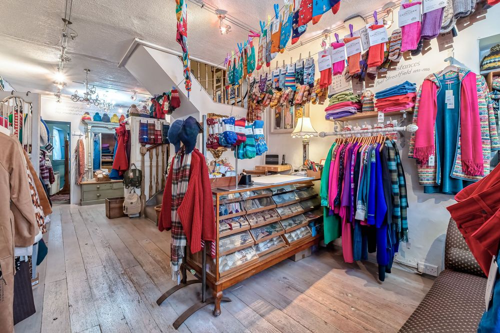 Interior view of a retail clothing store with colorful garments hanging on racks and displays.