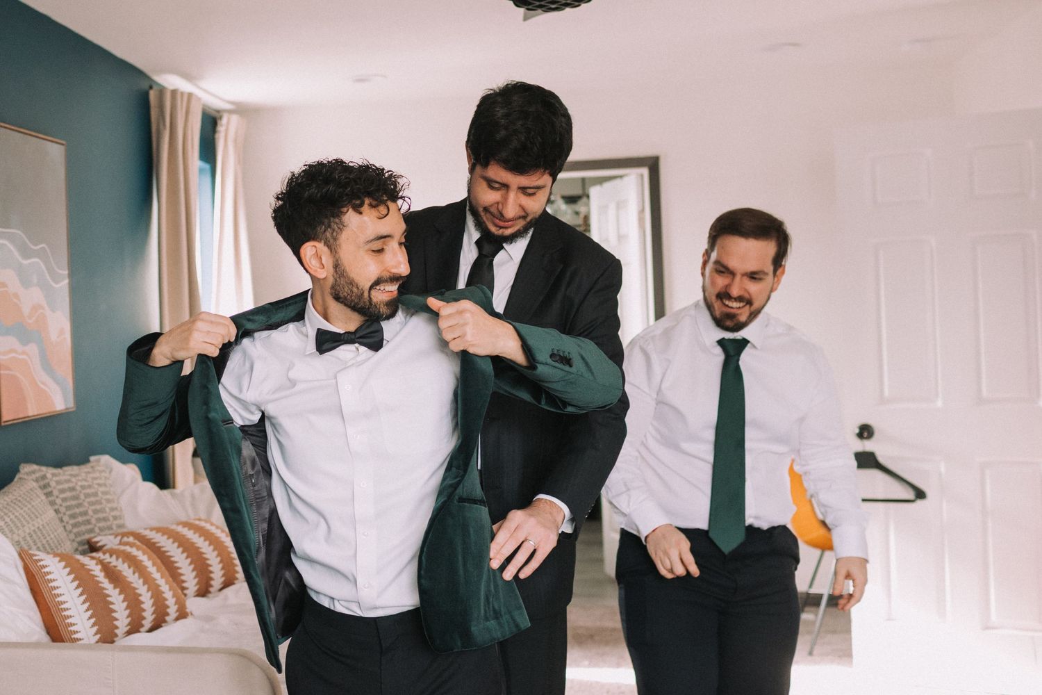 Wedding party members share candid moments while getting ready in formal attire.