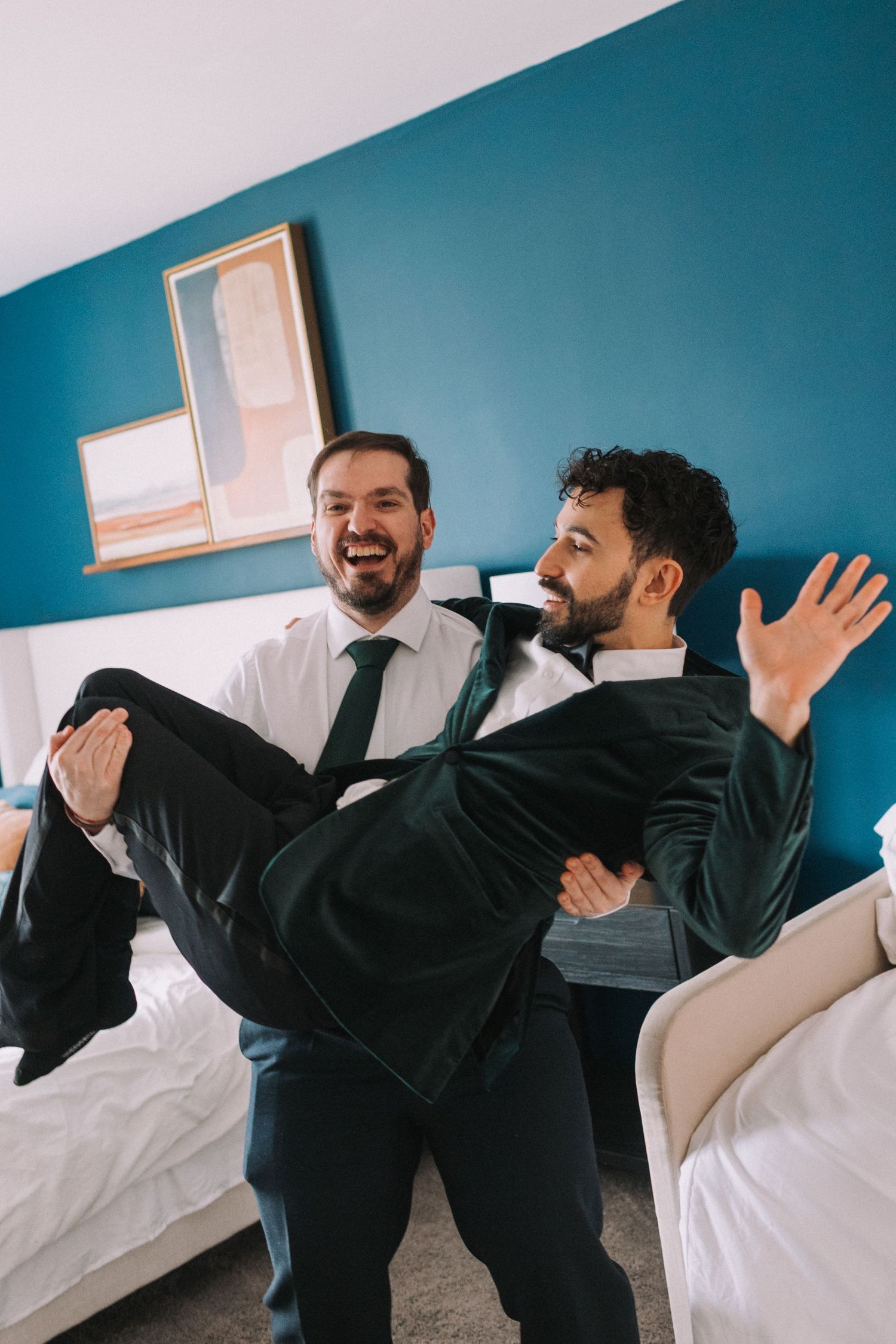 Two people in suits playfully demonstrate martial arts moves against a turquoise wall in a series of action shots.