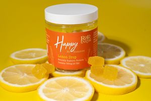 R&R Farms Happy Lemon Drop CBD gummies jar with lemon slices on bright yellow background.