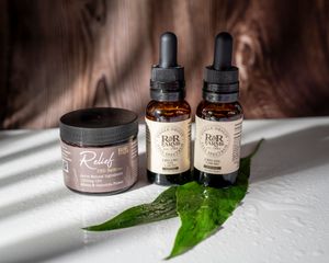 RnR Farms CBD wellness collection featuring Relief balm jar and two full spectrum CBD oil tinctures on green leaf.