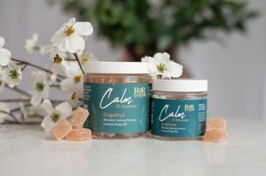 Two sizes of RnR Farms Calm CBD grapefruit gummies jars displayed with pink gummies and white flowers on neutral background.