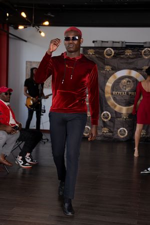 Dance instructor demonstrates hip hop moves on wooden floor in dance studio with spotlights.