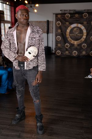 Model wearing zebra print jacket and distressed jeans poses against Royal Pride backdrop.