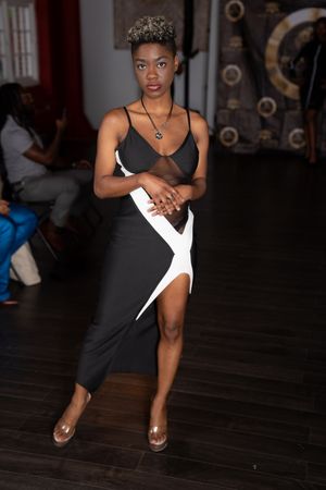 A dancer performs a dynamic contemporary dance movement sequence in a black outfit on a dark wooden floor.