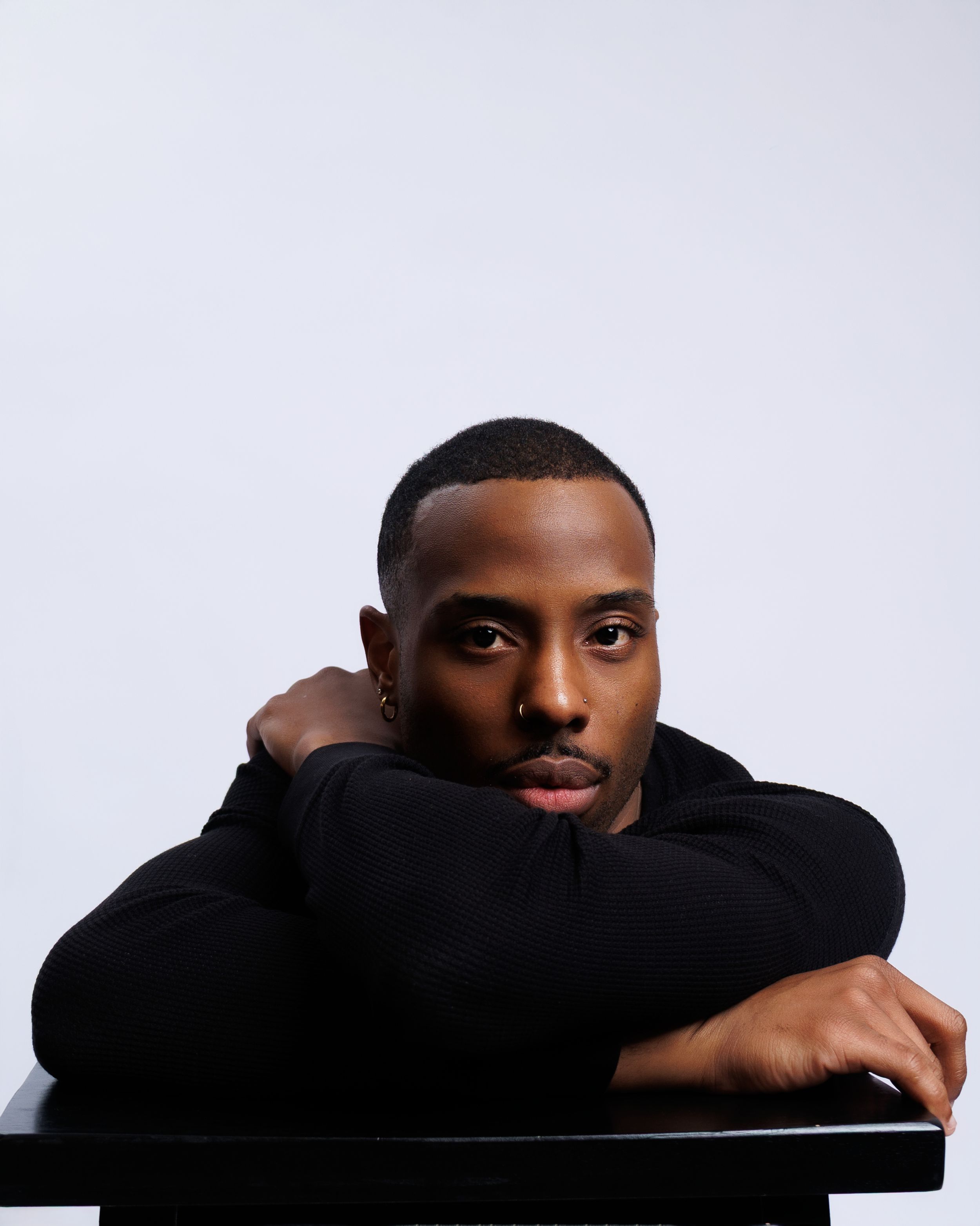 A series of four dramatic black and white portraits showing a figure in a black sweater against a white background.