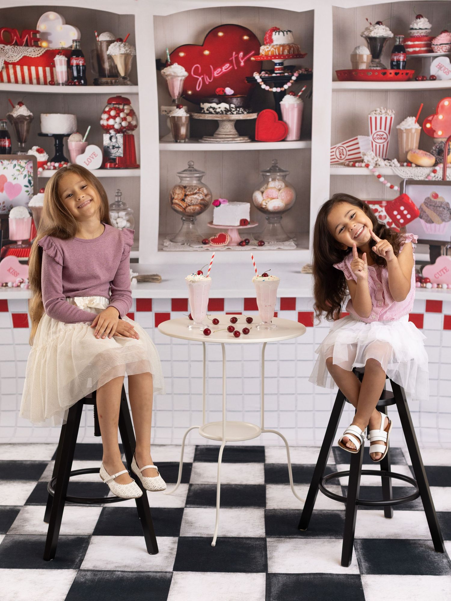 A retro-styled kitchen scene with red and white checkered tiles, black stools, and vintage diner-themed decor on display shelves.
