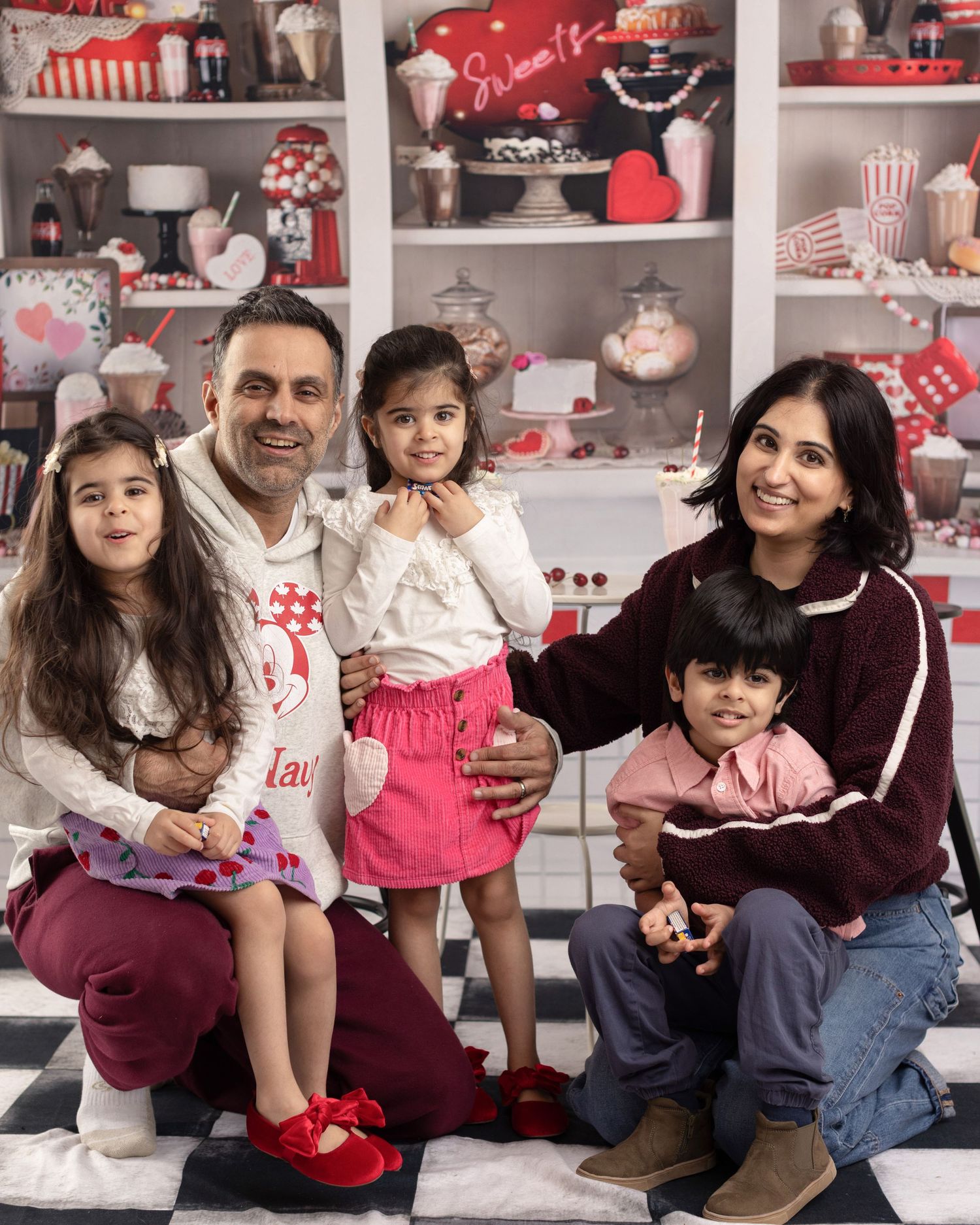 A family poses together in front of shelves displaying festive red and white holiday decorations.
