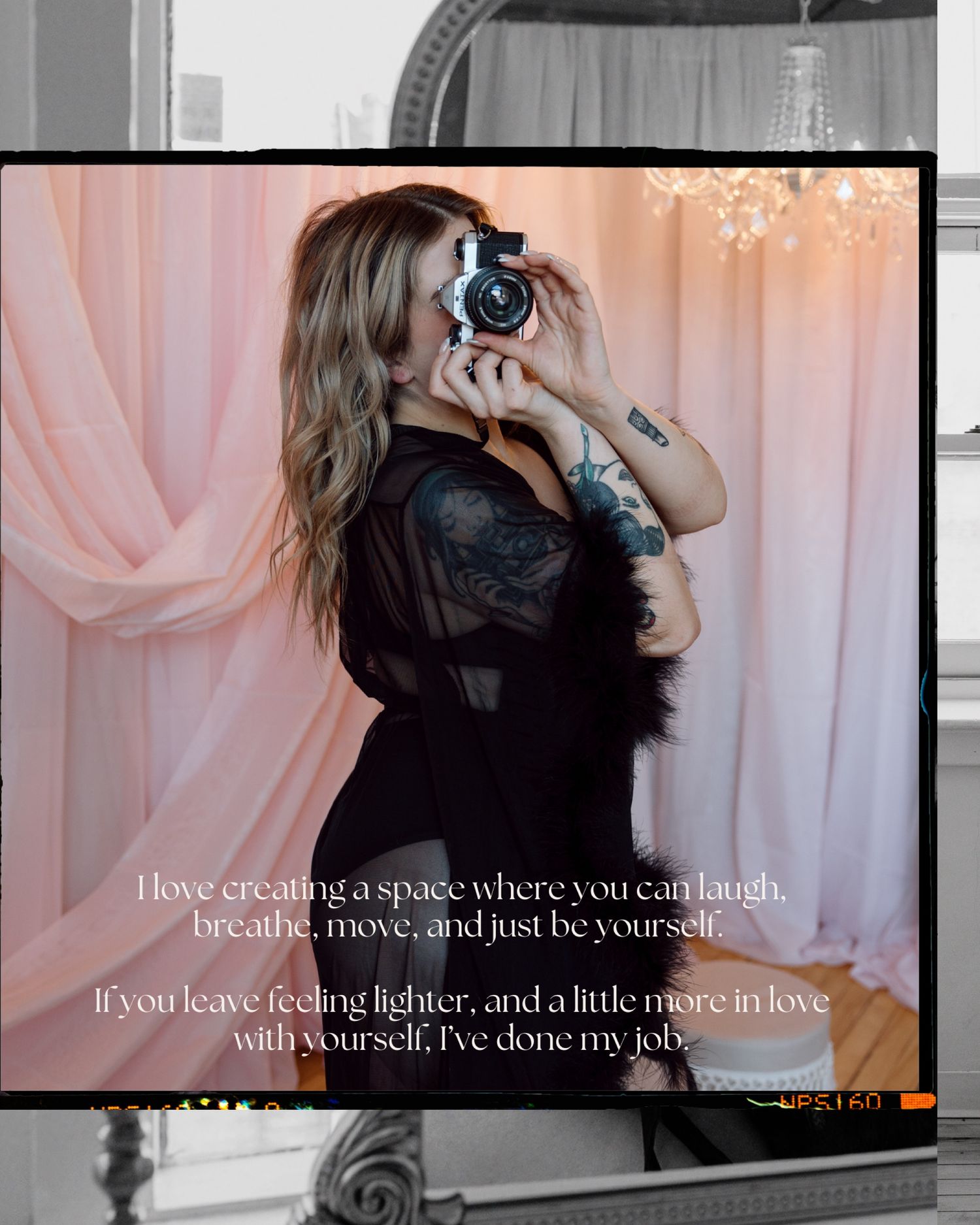 Tattooed photographer in black lingerie captures mirror selfie in pink-draped boudoir studio.