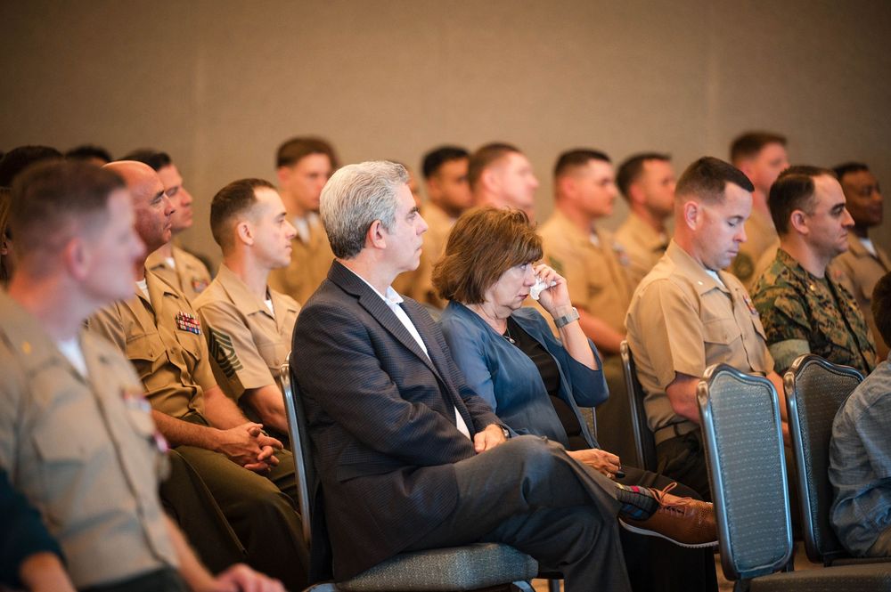 A row of audience members sitting in chairs laughing and smiling during a presentation or performance.