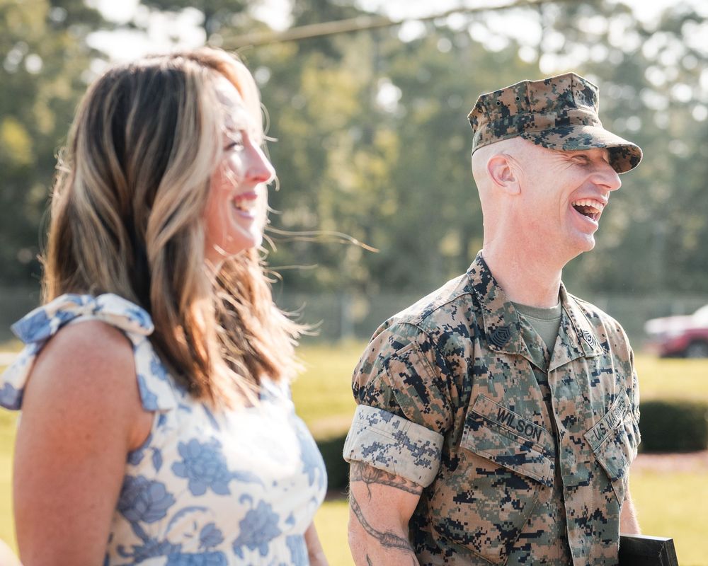 A couple in military uniform and floral dress share joyful moments together during an outdoor photo session.