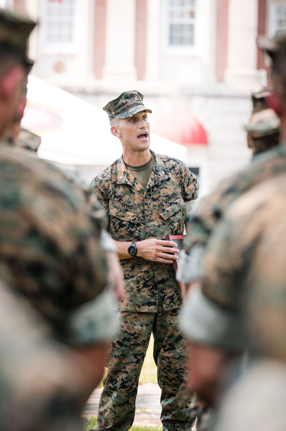 Military personnel in camouflage uniforms stand in formation during a training exercise or ceremony.
