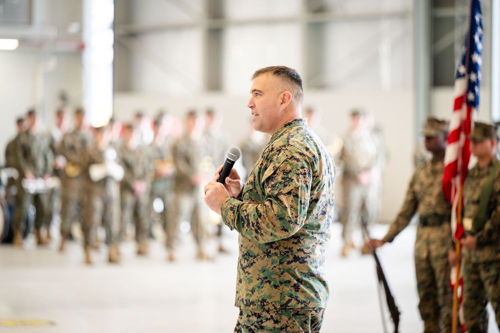 U.S. Marine Corps service members stand at attention during a military ceremony in a large indoor facility.