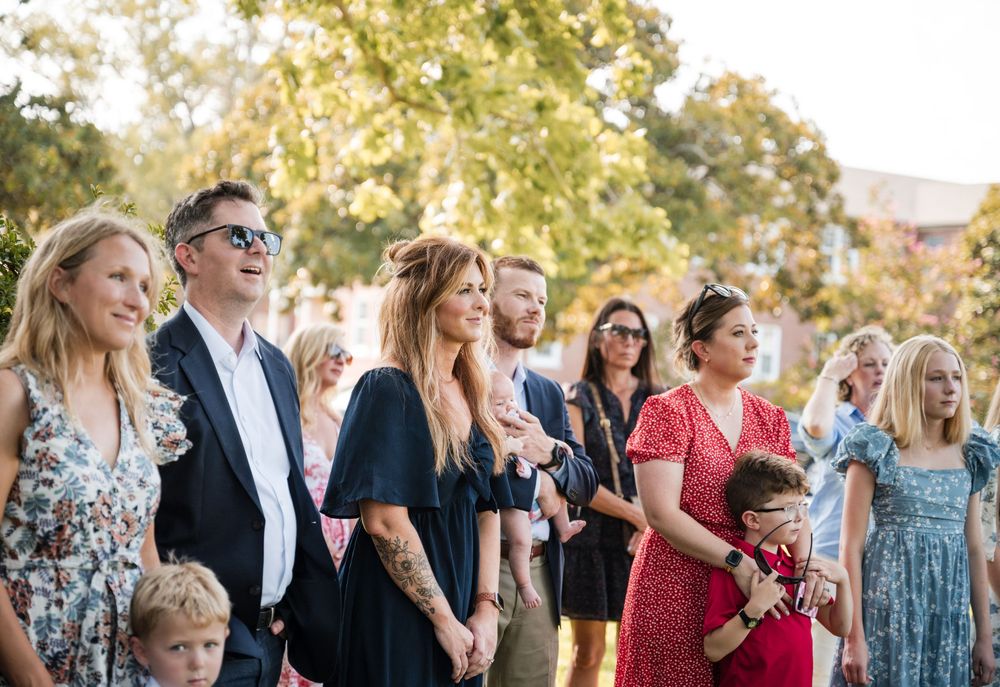 Wedding guests mingle and socialize during an outdoor celebration on a sunny afternoon.
