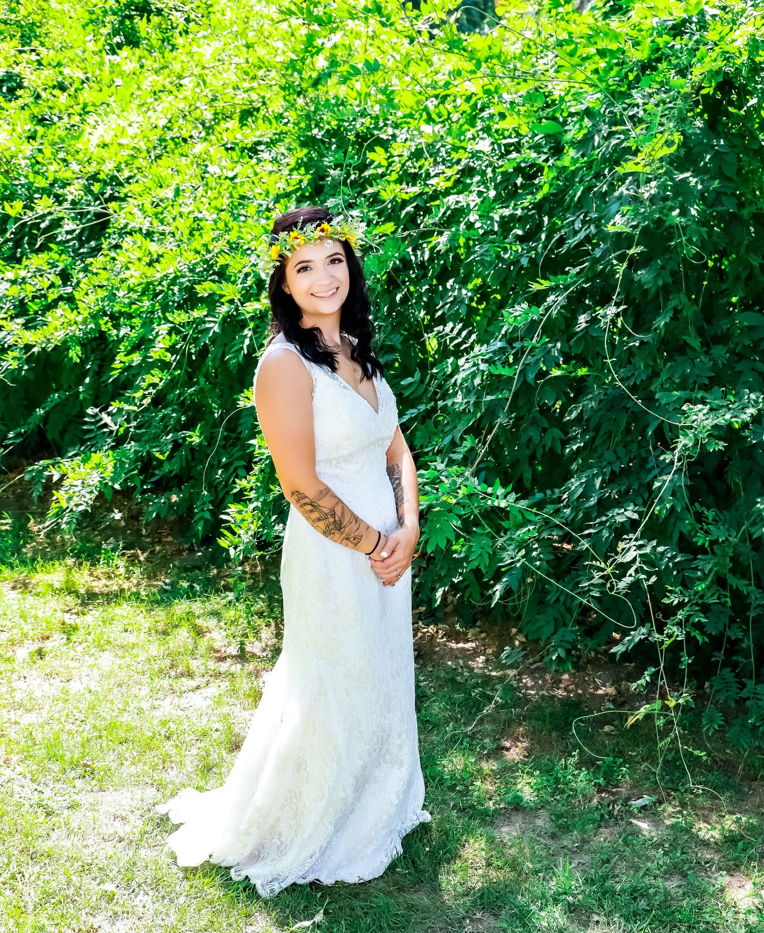 Outdoor bridal portraits in white lace dress against lush green foliage.