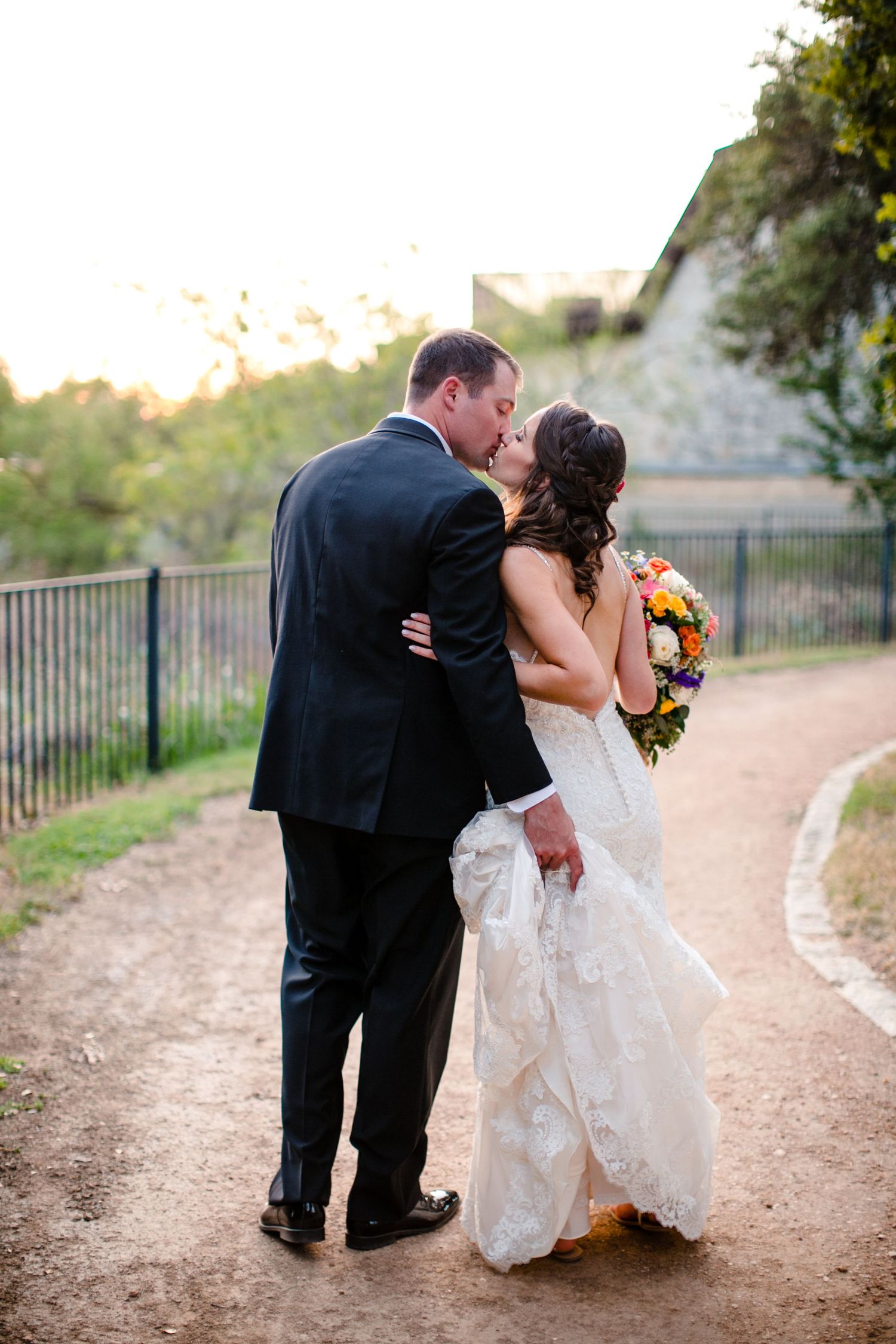 A bride and groom share romantic kisses on a dirt path at sunset in a series of four candid wedding photos.