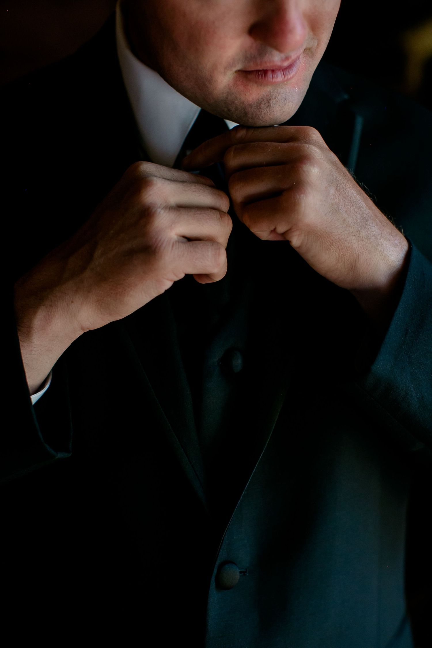 A sequence of dark moody portraits showing someone adjusting their collar in dramatic lighting.