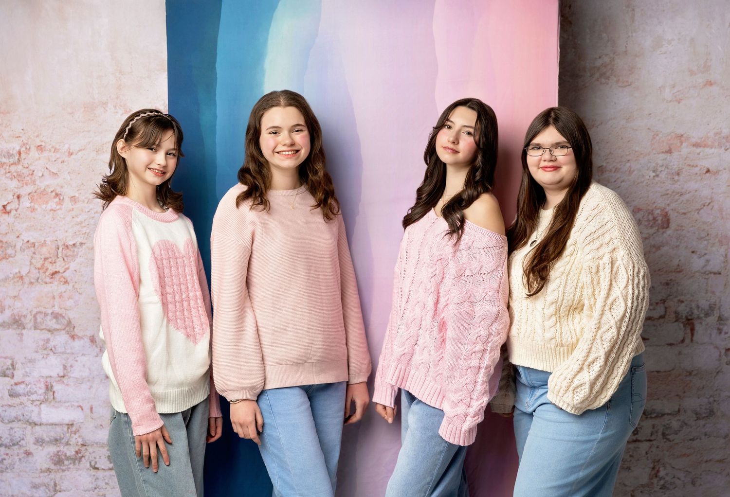 Four teen best friends pose together on pink and blue studio backdrop during a portrait session in New Hampshire