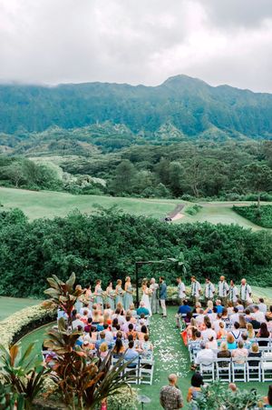 Outdoor wedding ceremony setup on a lush green hillside with mountain views in Hawaii.