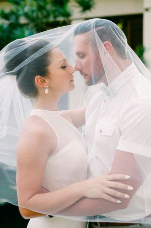 A romantic moment shared under a delicate wedding veil in soft, dreamy lighting.