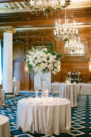 Luxurious ballroom wedding reception with crystal chandeliers, wood paneling and white floral centerpieces.