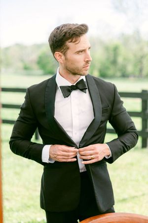Classic black tuxedo with bow tie photographed in an elegant outdoor setting.