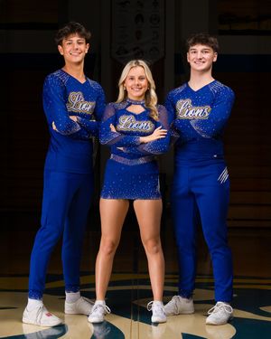 Three cheerleaders in sparkly royal blue uniforms with 'Bears' text pose together in a school gymnasium.
