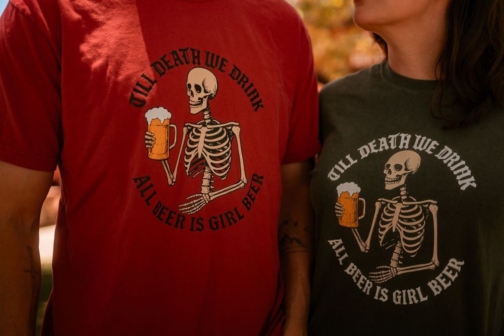 Couple wearing matching red and black skeleton "Till Death We Drink, All Beer Is Girl Beer" graphic tees.