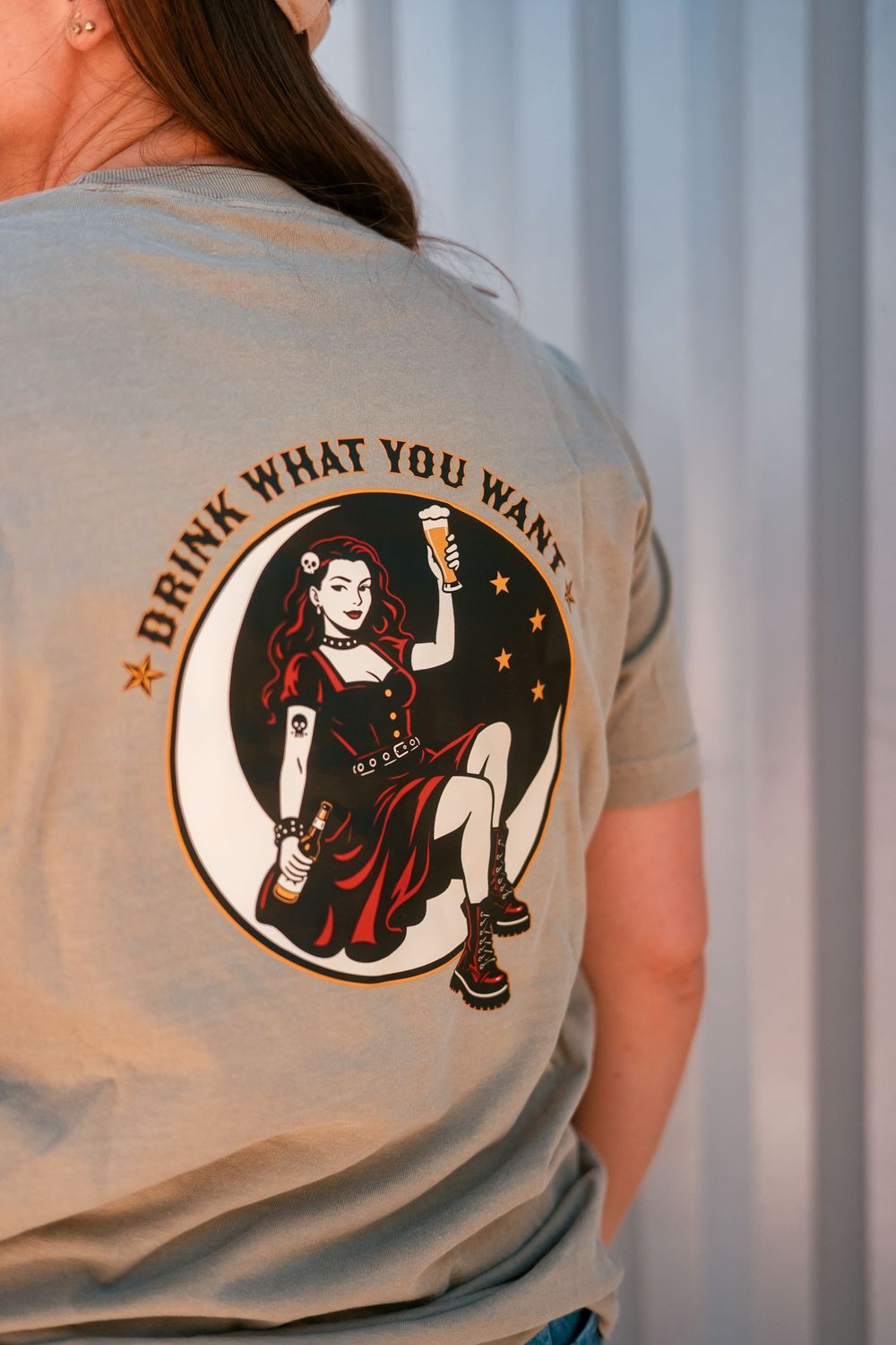 Gray t-shirt back print featuring pin-up girl holding beer with "Drink What You Want" text graphic.