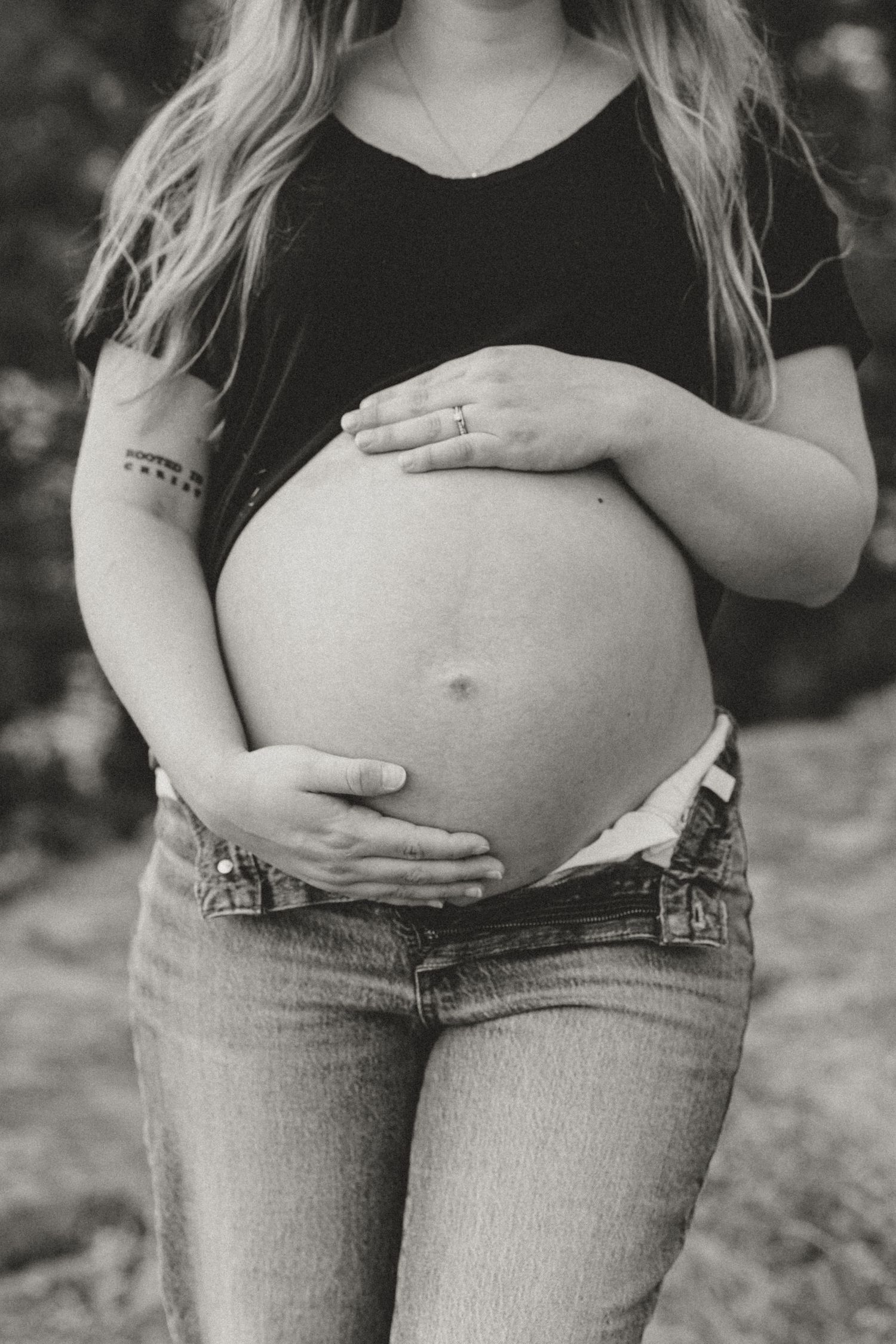 Close up black and white shot of pregnant belly with hands lovingly placed on bump.