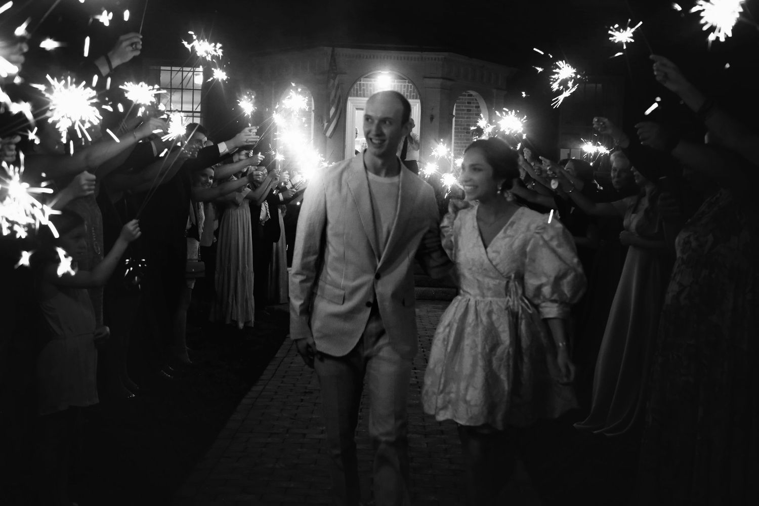 Nighttime sparkler exit celebration with couple walking through glowing lights.