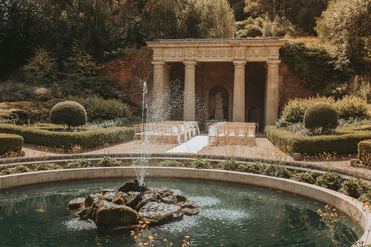 Elegant garden pool and stone architecture creates romantic wedding venue setting.