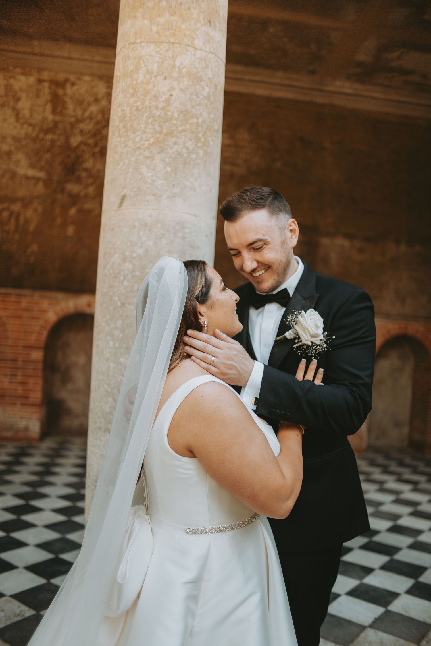 Candid moment between newlyweds laughing together in classical venue setting.
