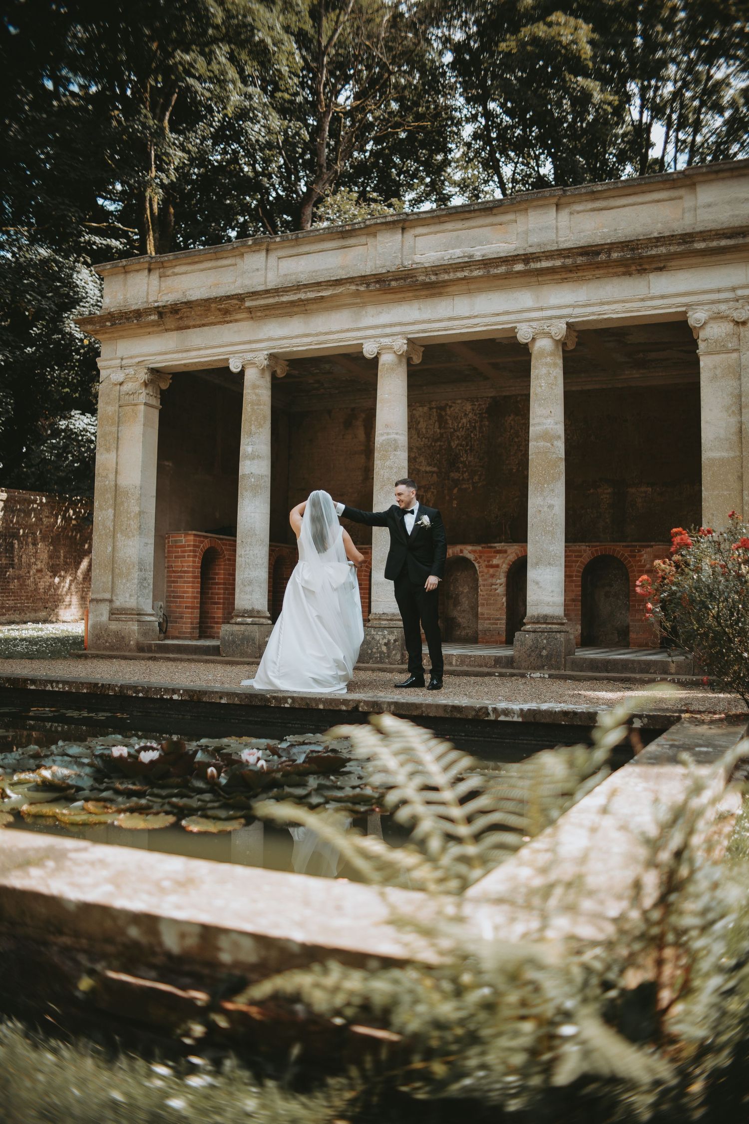 Wedding photography session at historic venue featuring stone columns and red flowers.